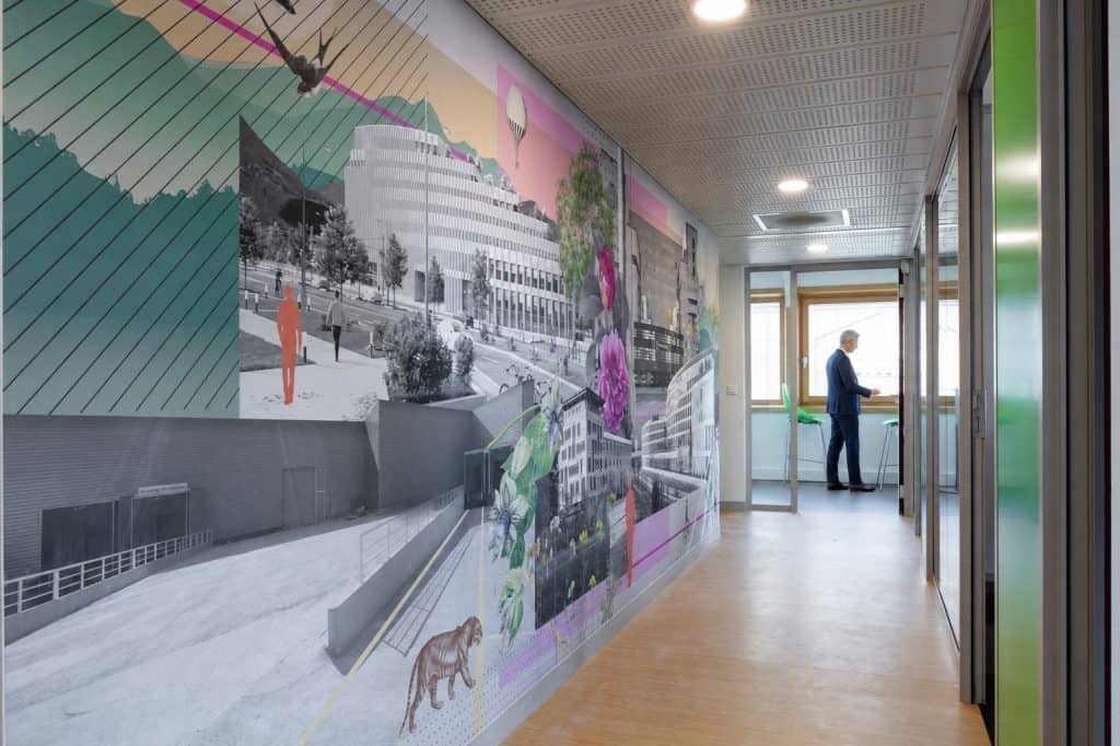 Fresque de la ville le long d’un couloir de l’agence du Groupe AXITE à Grenoble, un bureau vitré au fond