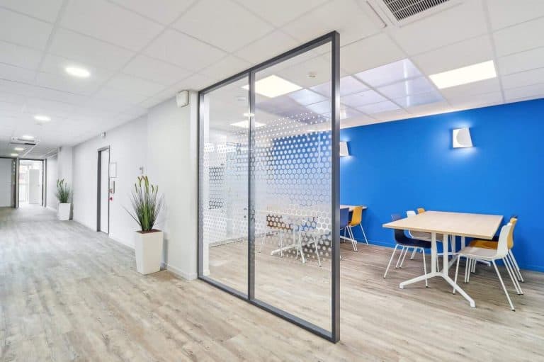 Couloir et salle de réunion vitrée des bureaux d’Erilia à Annemasse, rénovés par INSIDE