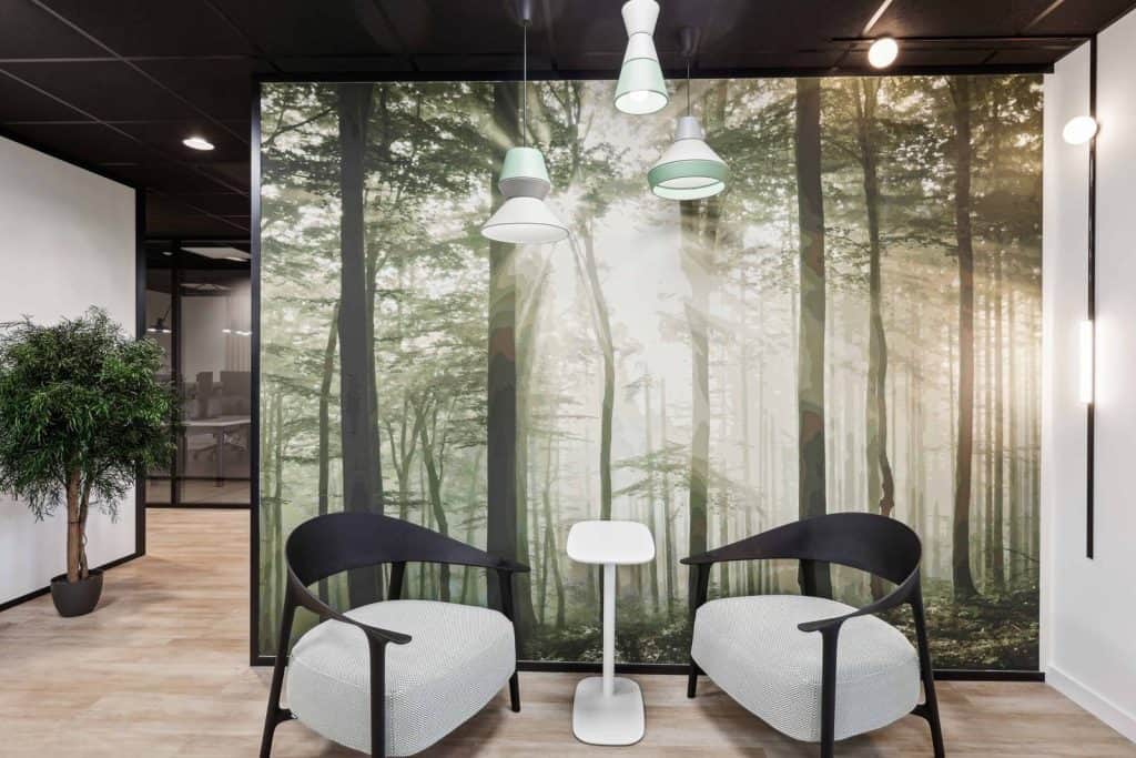 Coin salon meublé par WOM chez Access Group à Annecy-le-Vieux, devant un papier peint forêt
