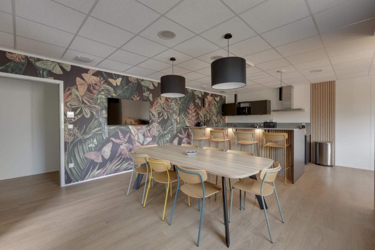 Espace de restauration de Care TP à L’Albenc, équipé par WOM : grande table en bois et papier peint végétal