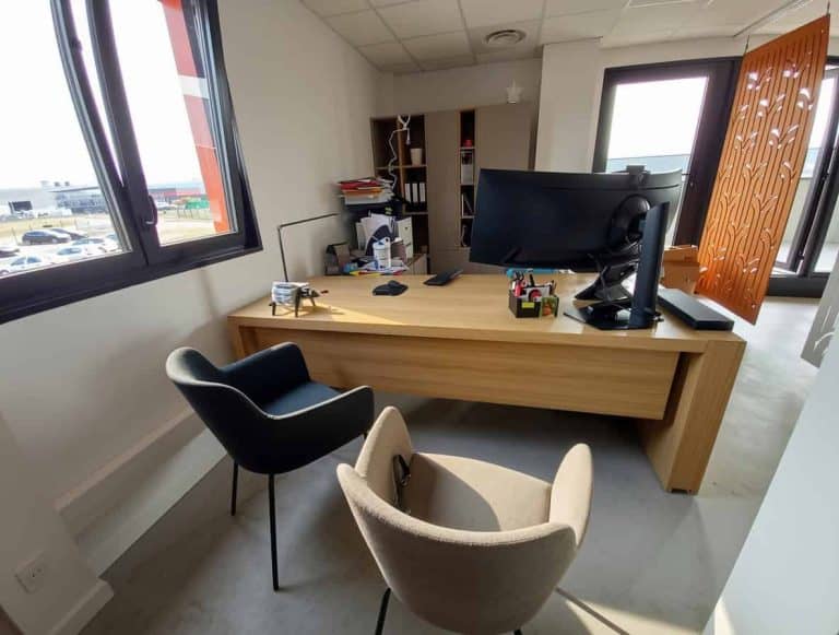 Bureau de CJMETAL à Saint-Étienne-de-Saint-Geoirs, meublé par WOM : bureau en bois, fauteuils et cloison décorative ajourée