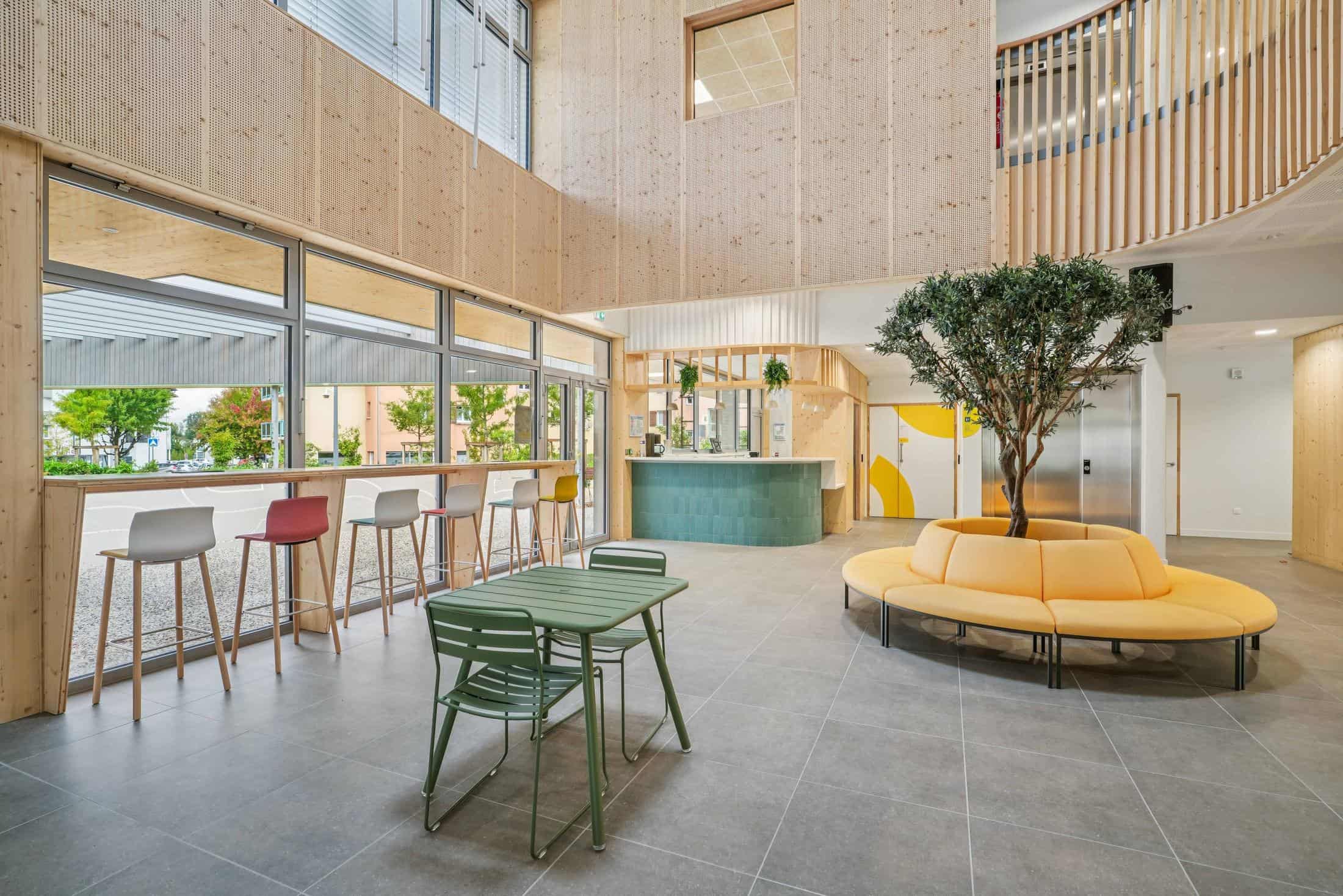 Hall de L’Esquisse, tiers-lieu de Grésy-sur-Aix meublé par WOM : banquette ronde autour d’un olivier