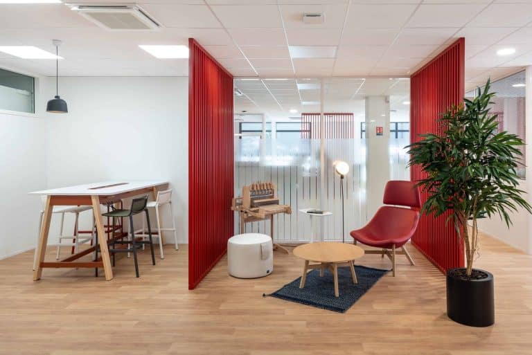 Espace informel des bureaux de Serge Ferrari à Rochetoirin, meublé par WOM : cloisons rouges, table haute, fauteuil et table basse